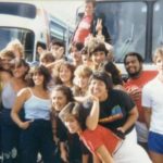 Group of members huddled in front of the tour buses, posing for the photo